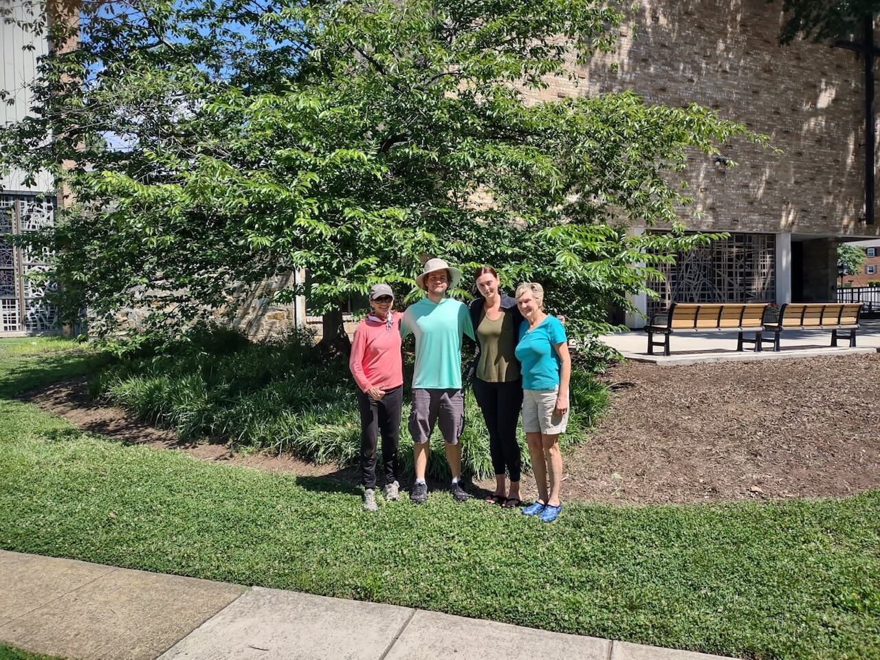 group photo of people underneath a tree in front of the church