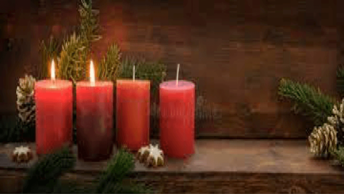 Four Advent Candles sit on a wooden bench with pinecones and garland. Two candles are lit.