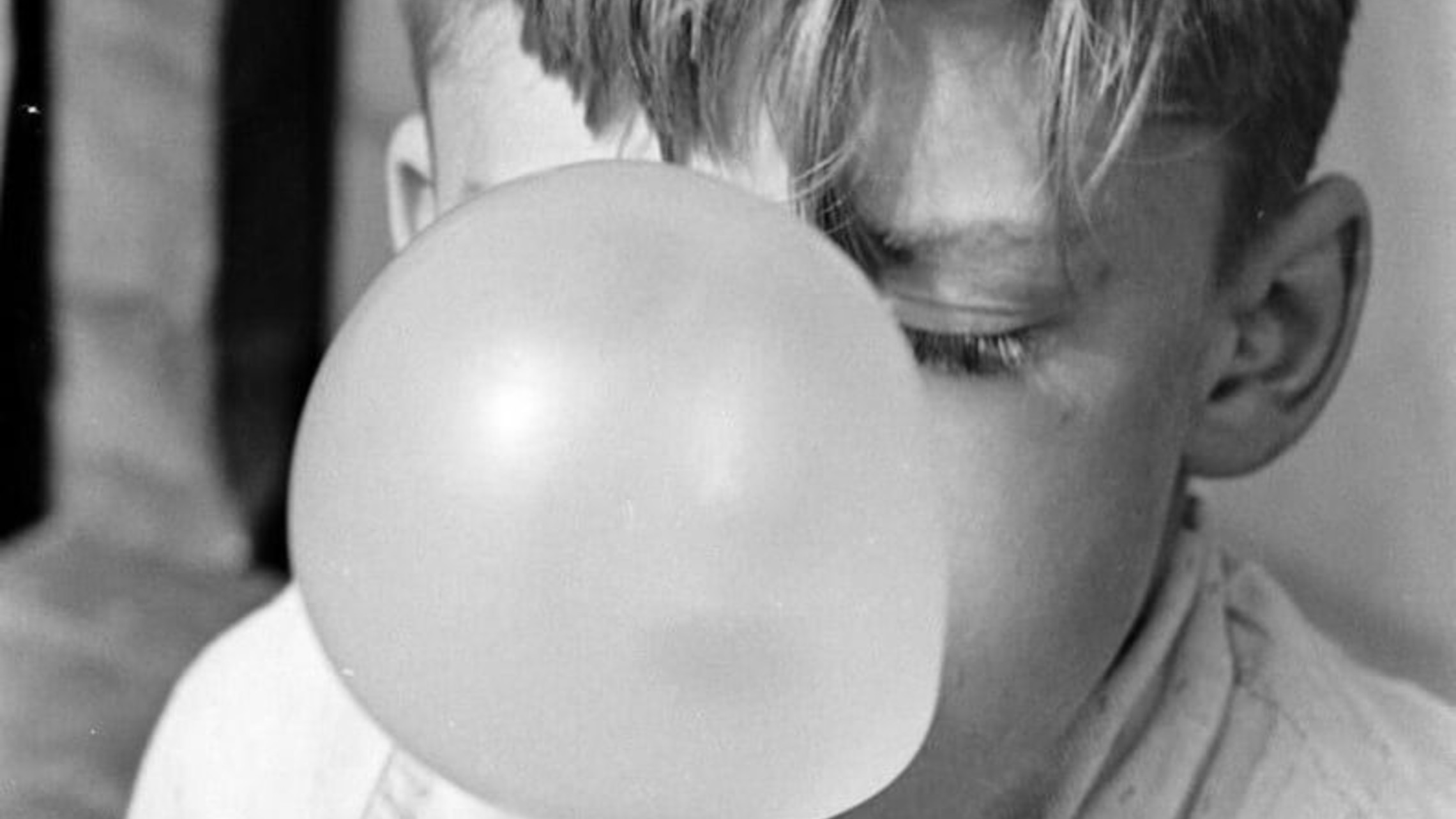 black and white photo of child blowing bubble gum