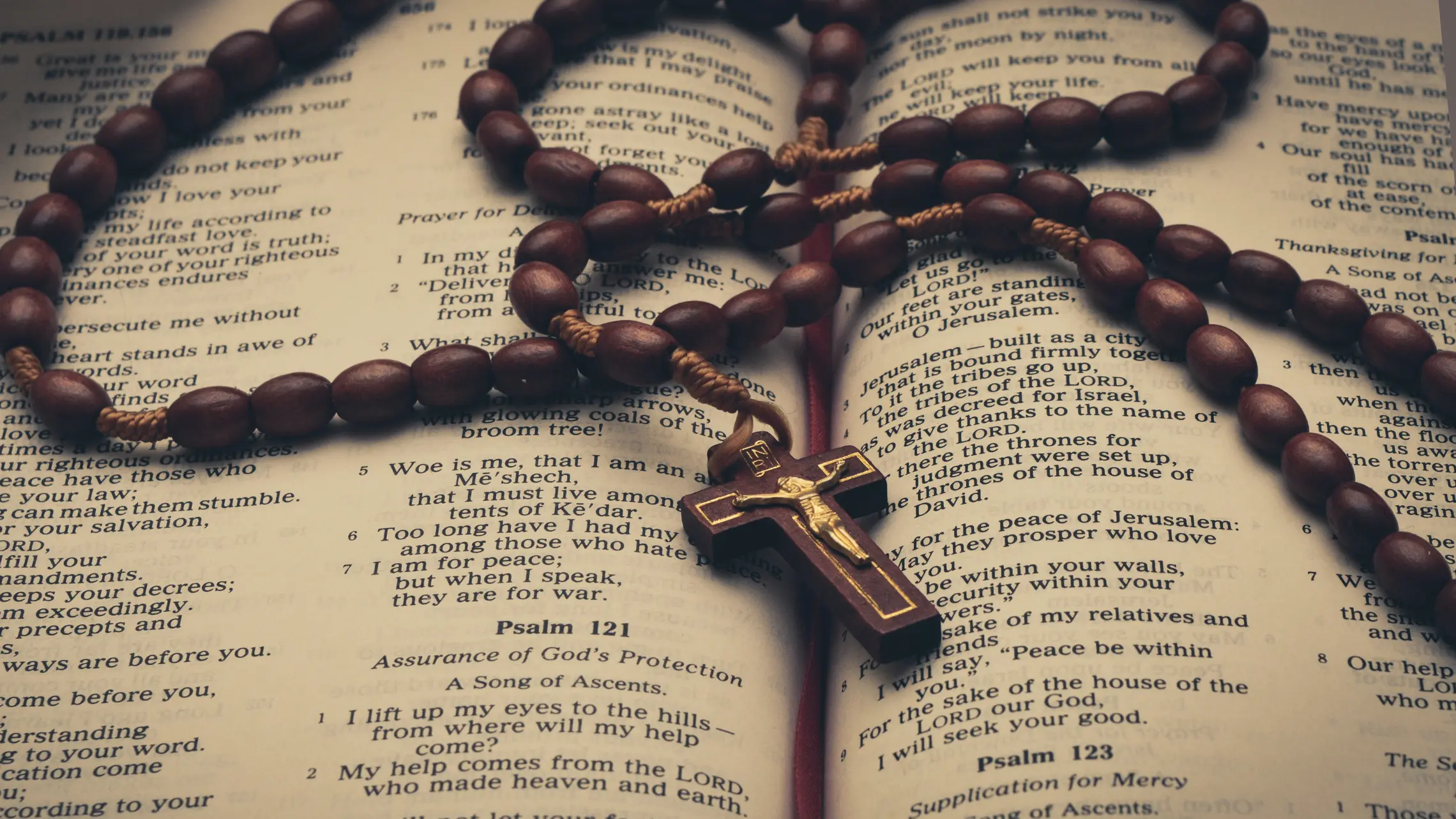 photo of an open bible turned to Psalms, with a rosary on top of the pages