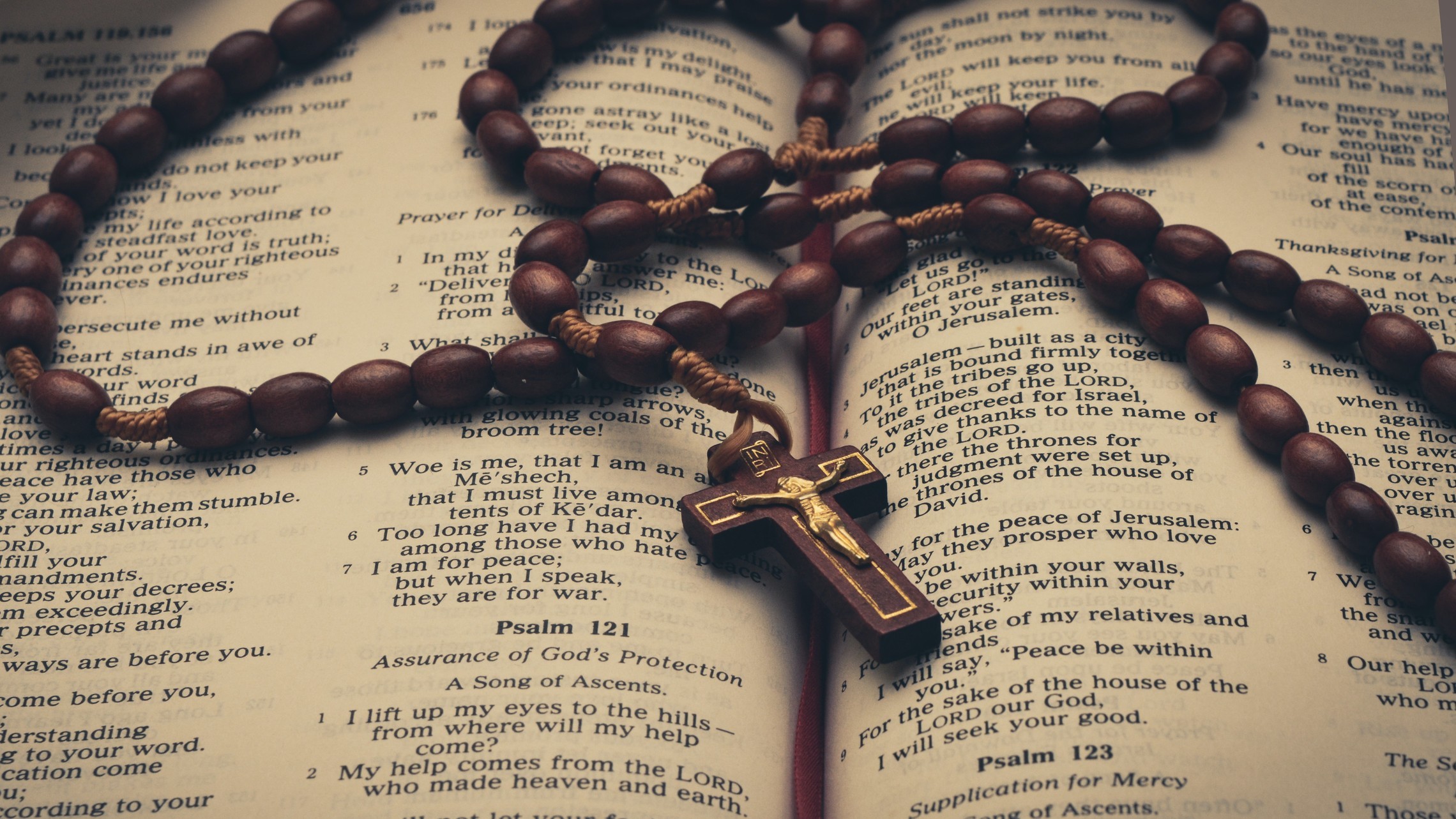 photo of an open bible turned to Psalms, with a rosary on top of the pages