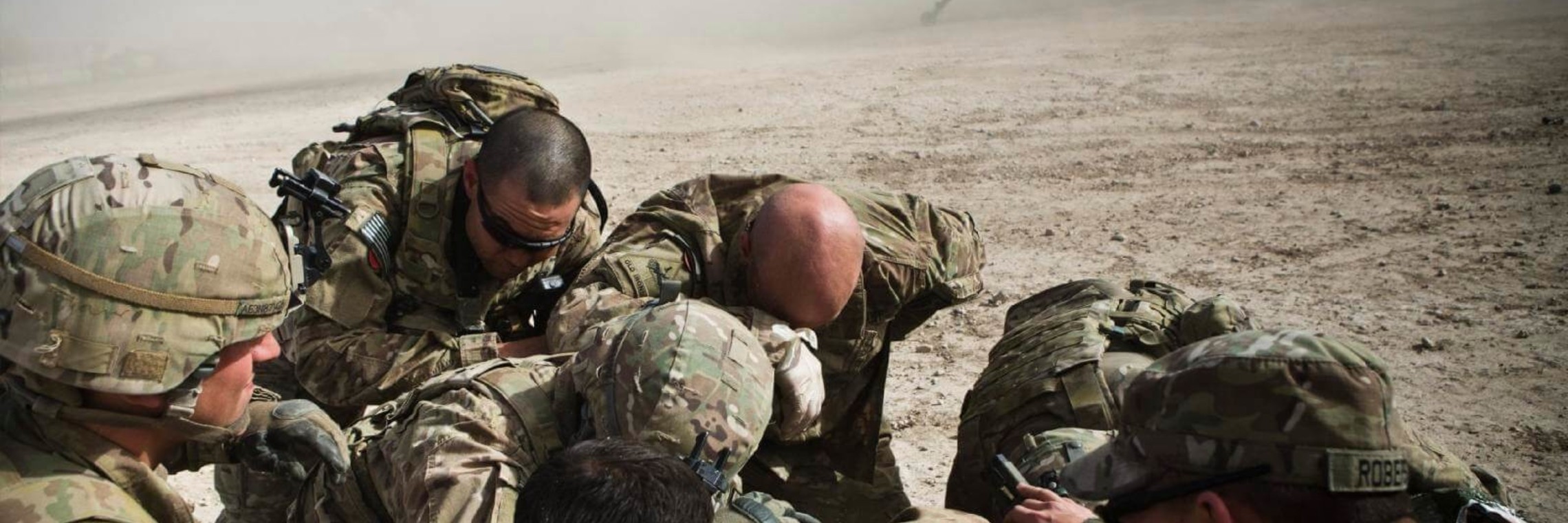 photo of a huddled group of soldiers in the desert in Afghanistan