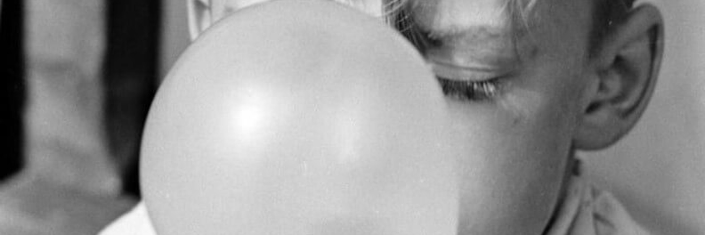 black and white photo of child blowing bubble gum