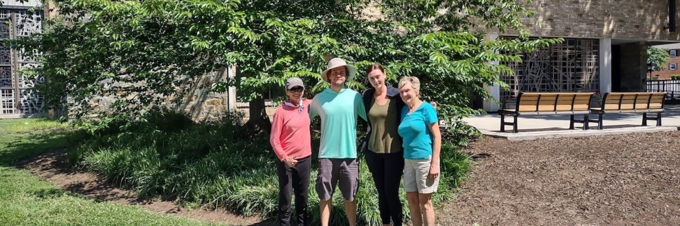 group photo of people underneath a tree in front of the church