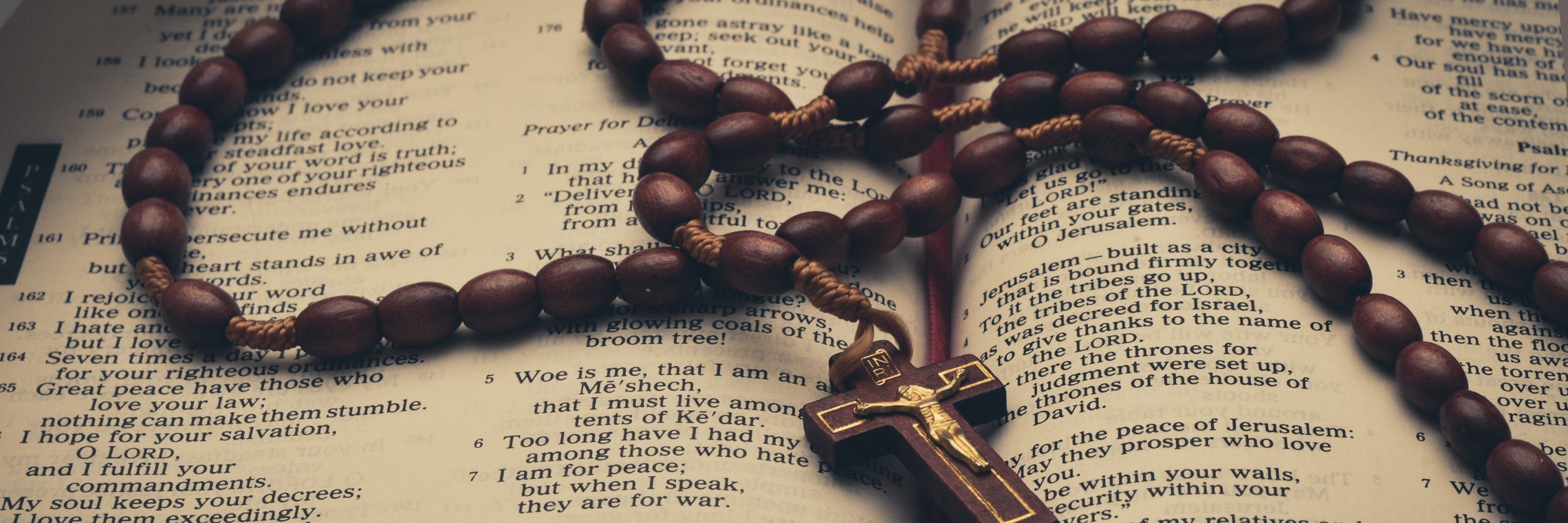 photo of an open bible turned to Psalms, with a rosary on top of the pages