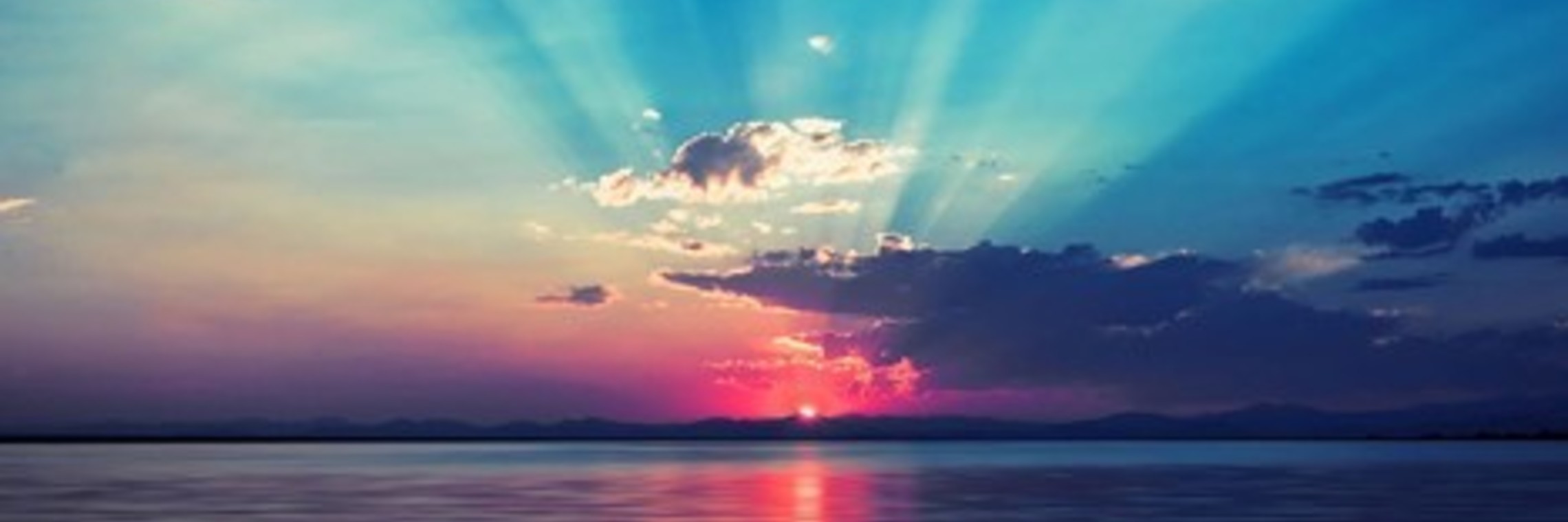 hues of blue, pink, gold and red line a calm sea. the sun goes down. 
