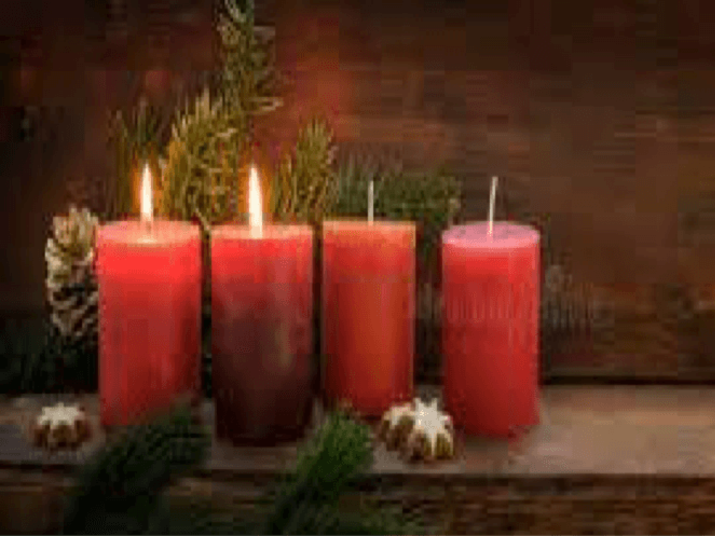 Four Advent Candles sit on a wooden bench with pinecones and garland. Two candles are lit. 