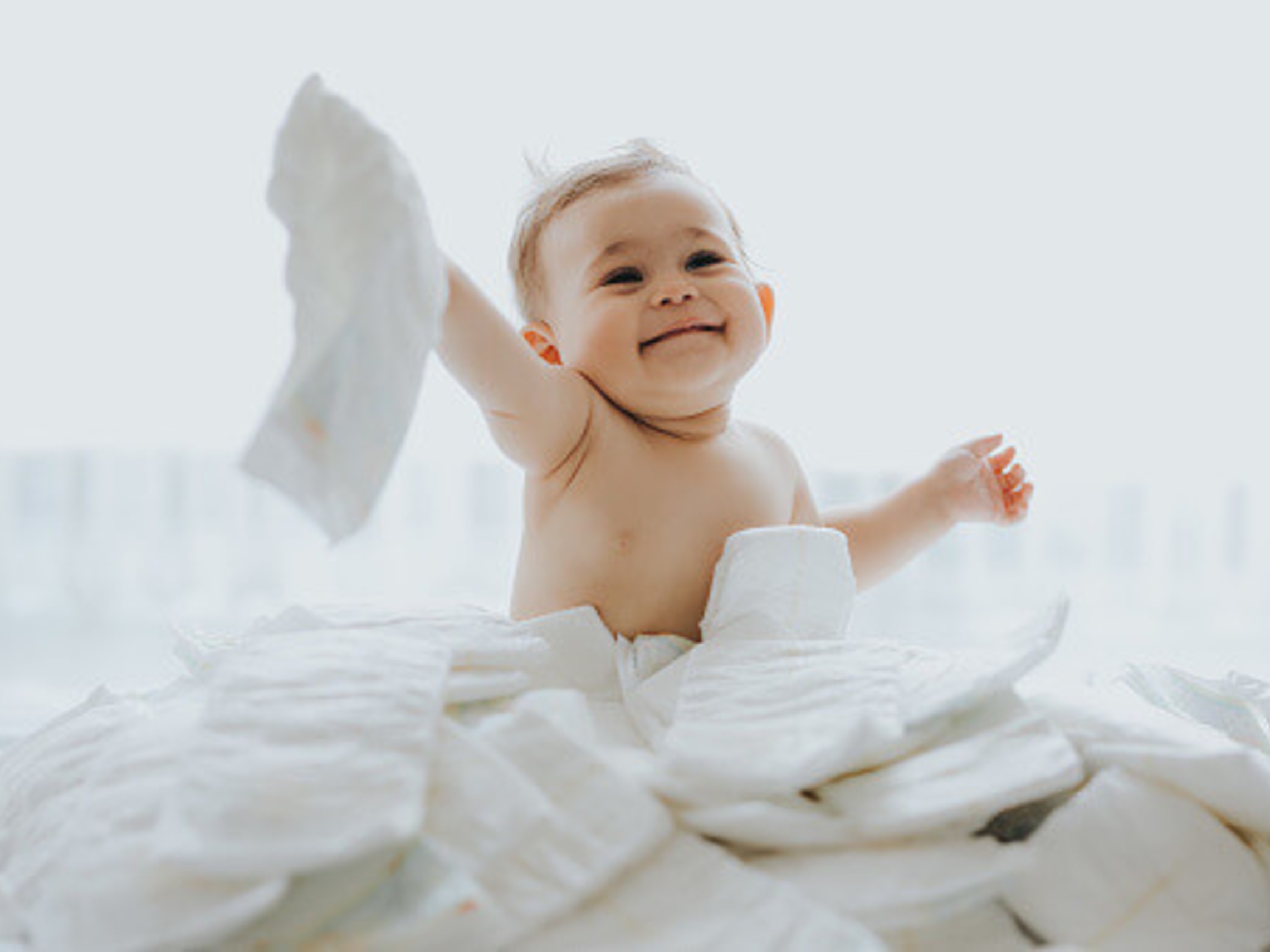photo of small baby playing in a pile of new diapers